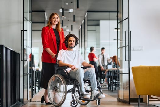 A business leader with her colleague, an African-American businessman who is a disabled person, pass by their colleagues who work in modern offices.