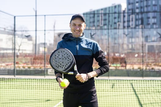 Man playing padel in a green grass padel court indoor behind the net. High quality photo