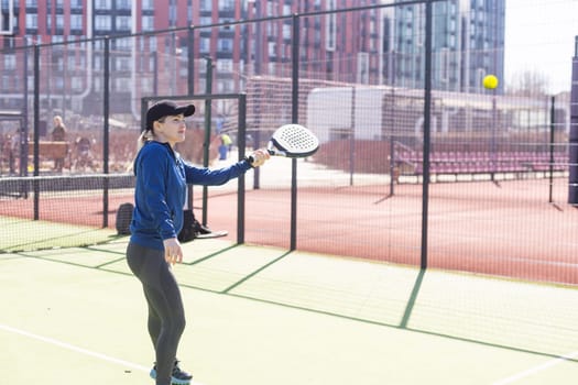 One woman with racquet and ball behind the net in paddle tennis court ready for training. High quality photo