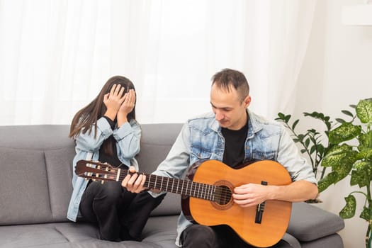A father teaching his daughter how to play guitar. High quality photo