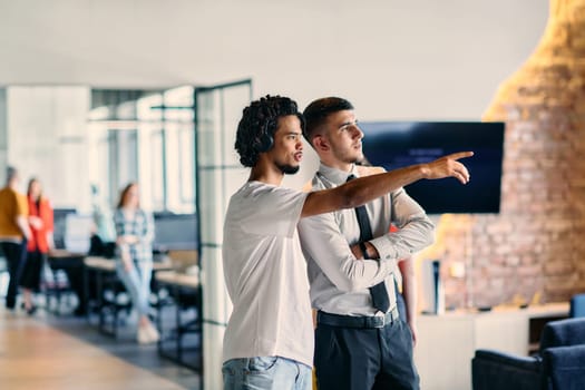 A group of colleagues, including an African American businessman and a young leader in a shirt and tie, pose together in a modern coworking center office, representing a dynamic blend of professionalism and collaboration.