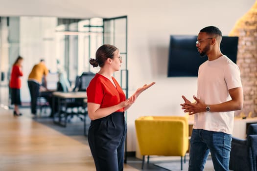 Young business colleagues, including an African American businessman, engage in a conversation about business issues in the hallway of a modern startup coworking center