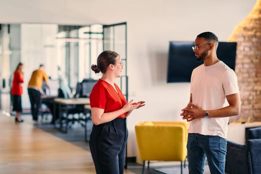 Young business colleagues, including an African American businessman, engage in a conversation about business issues in the hallway of a modern startup coworking center