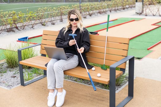 Woman using a laptop and mobile phone on the golf course. High quality photo