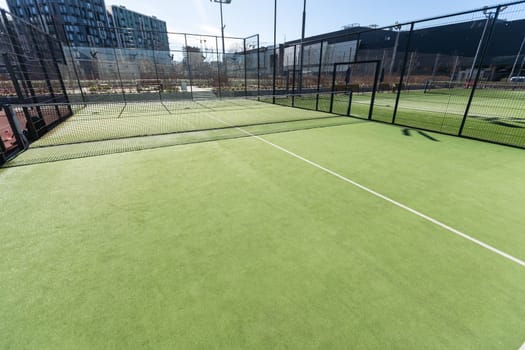 Landscaped areas of a residential development with a tennis court with high Plexiglas and metal fences. High quality photo