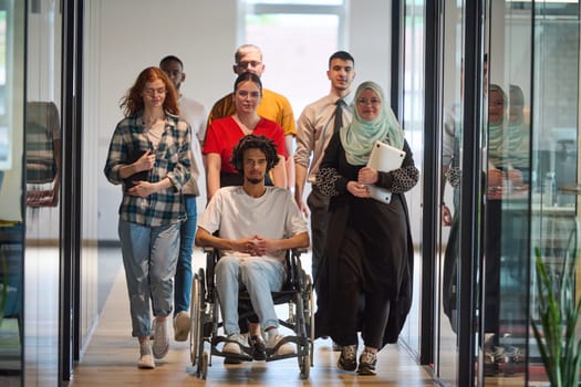 A diverse group of young business people congregates within a modern startup's glass-enclosed office, featuring inclusivity with a person in a wheelchair, an African American young man, and a hijab muslim woman