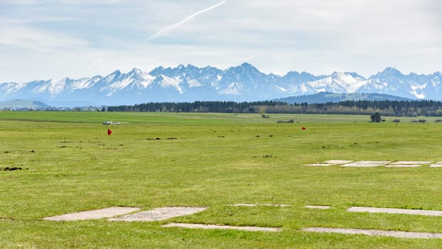 View of snow capped Tatra mountains from sport grass airfield in Nowy Targ