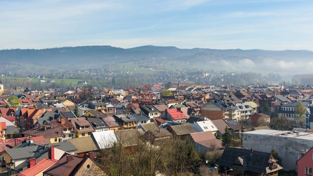 Panoramic view of the rooftops of Nowy Targ with the morning fog in the background