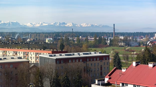 Panoramic view of the rooftops of Nowy Targ with snow capped Tatra mountains in the background