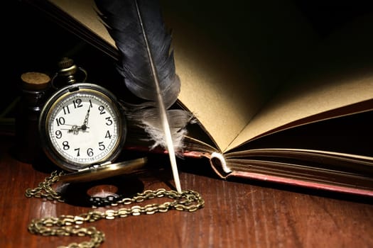 Nice vintage still life with pocket watch and feather near old book