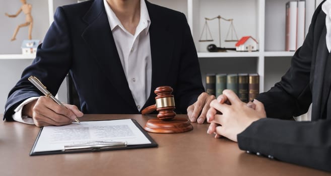 Close-up of lawyer and businesswoman signing legal documents of doing business in lawyer's office room.