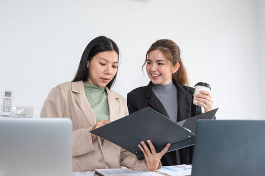 Two businesswomen discuss the company's documentation. Working together in the office.
