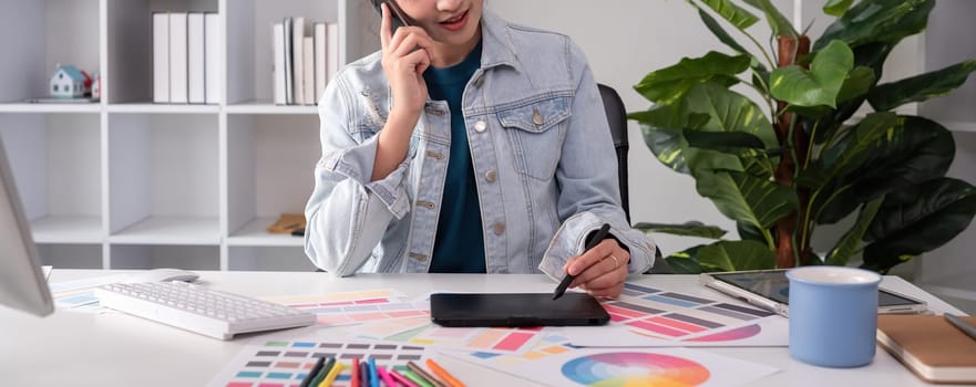 A designer working in graphic design talks in a meeting over tones while choosing colors for work on a computer at his desk at home..