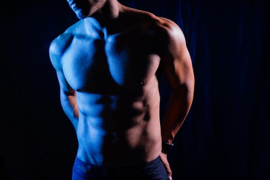 Confident, attractive shirtless muscular young man topless in a studio