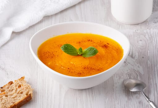 Pumpkin soup on a white wooden table.