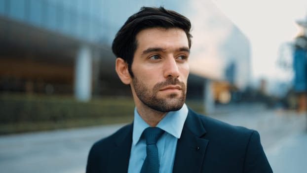 Closeup portrait of professional business man standing at camera at city view. Skilled project manager standing with cool pose with blurred background. Handsome investor pose at camera. Exultant.