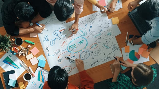 Group of business people writing and making mind map to brainstorming marketing idea at meeting. Top aerial view of investors sharing plan or strategy by using sticky notes. Top view. Convocation.