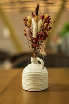 Vase with dried flowers on wooden table