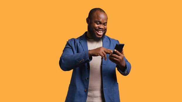 Happy man adding payment method on phone website, delighted to take advantage of promotions, studio background. Person thrilled to do internet shopping, typing credit card data on smartphone, camera B