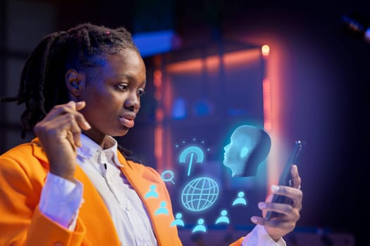African american woman at home using mobile phone, interacting with artificial intelligence assistant using AR. Person working with augmented reality, solving tasks on internet helped by AI