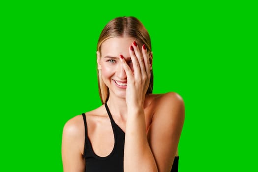 Smiling Young Woman in Casual Outfit Posing Against Green Background in studio
