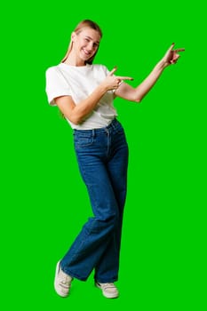 Young Woman Pointing at Something against green background in studio