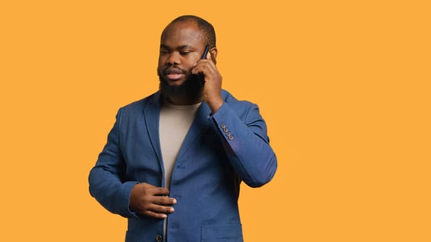 African american man disagreeing with friend during telephone call, shaking head, studio background. BIPOC person talking on phone with mate, unhappy with proposal, refusing, camera A