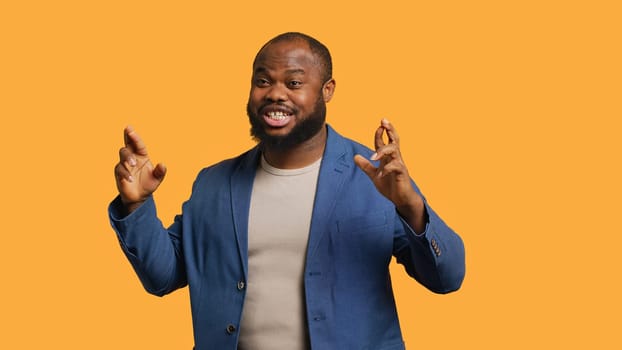 Portrait of upbeat african american man crossing fingers, making wish, isolated over yellow studio background. Jolly BIPOC person hoping for good luck, waiting for miracle, camera A