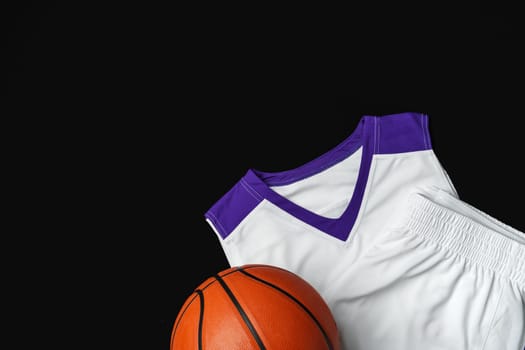 A basketball rests against a white and purple basketball jersey with a v-neck collar on a contrasting black backdrop, highlighting the textures and details of the sports equipment and apparel commonly used in basketball games.