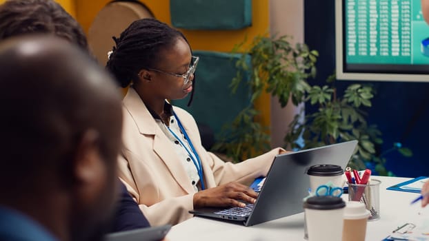 Business associates working together on a project in a boardroom, reviewing success metrics and key performance indicators to measure progress. Employees accomplishing enterprise goals. Camera A.