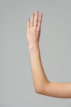 Female hand gesturing numbers on gray background close up