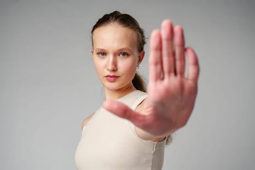 Young Woman Making Stop Sign With Hands on gray background in studio