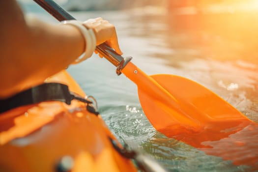 Kayak paddle sea vacation. Person paddles with orange paddle oar on kayak in sea. Leisure active lifestyle recreation activity rest tourism travel.