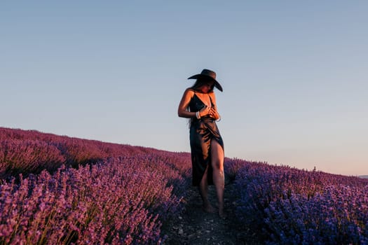 Close up portrait of young beautiful woman in a white dress and a hat is walking in the lavender field and smelling lavender bouquet.