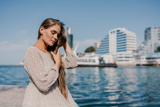 A woman with long hair is sitting on a dock by the water. She is wearing a white dress and she is looking at the water. The scene has a calm and peaceful mood