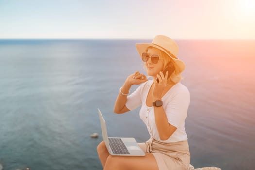 Freelance women sea. She is working on the computer, talking on the phone in the open air with a beautiful view of the sea. The concept of remote work