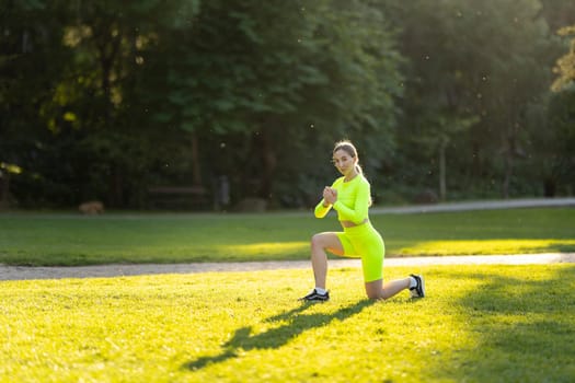 A woman in a neon green outfit is doing a yoga pose on a grassy field. The bright colors of her outfit and the lush green grass create a cheerful and energetic atmosphere