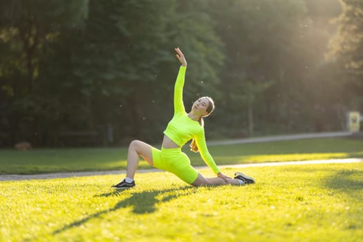 A woman in a neon green outfit is doing a yoga pose on a grassy field. The bright colors of her outfit and the lush green grass create a cheerful and energetic mood