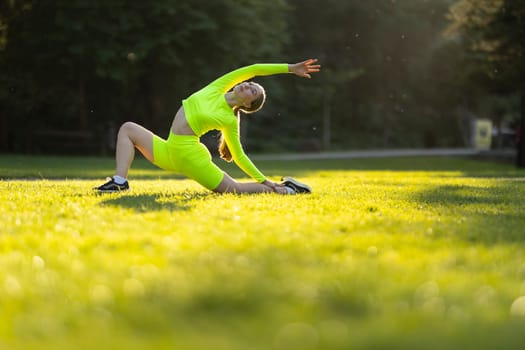 A woman in a neon green outfit is doing a yoga pose in a grassy field. The bright colors of her outfit and the green grass create a cheerful and energetic mood. Concept of health and wellness