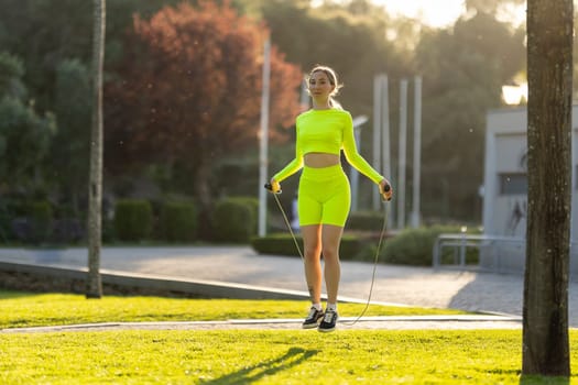 A woman in a neon yellow outfit is jumping rope in a park. The scene is bright and cheerful, with the woman's outfit and the green grass creating a sense of energy and positivity