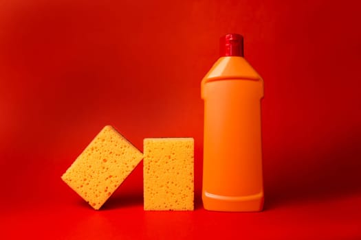 yellow sponge and orange bottle with cleaning on a red background