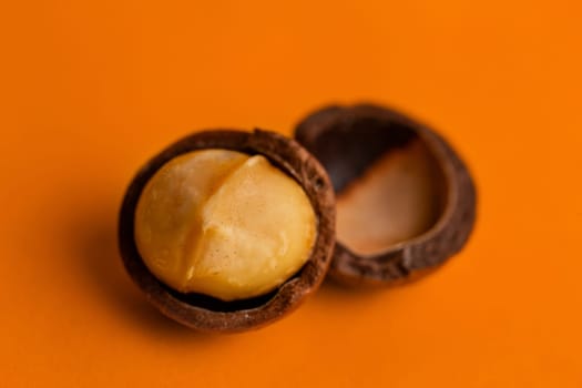 split macadamia nut close-up on an orange background.