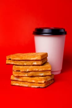 white cup of coffee and three waffles on a red background