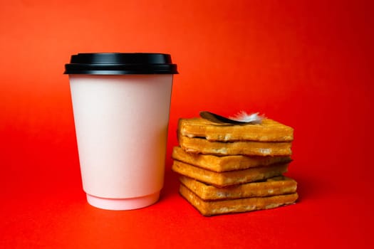 paper coffee cup with waffles and a light pen on a red background.