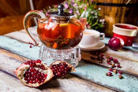 red fruit tea in a teapot with pomegranate on the table.