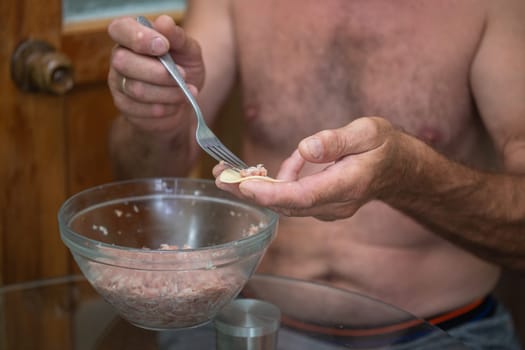 a man prepares dumplings with minced meat.