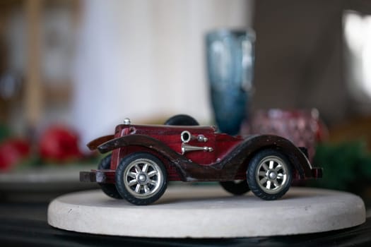 small wooden model of an old retro car, on a white podium