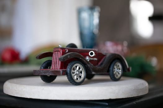 small wooden model of an old retro car, on a white podium