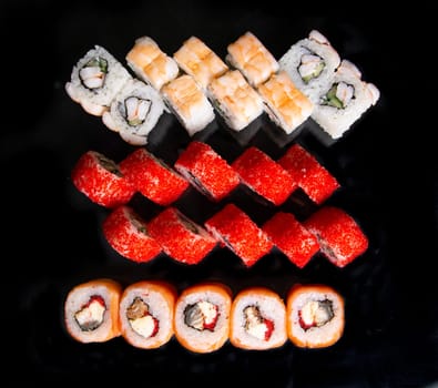 set of Japanese sushi rolls on a black background top view.