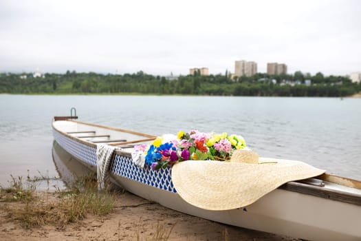 a boat with flowers and a hat on the river bank on a summer day.